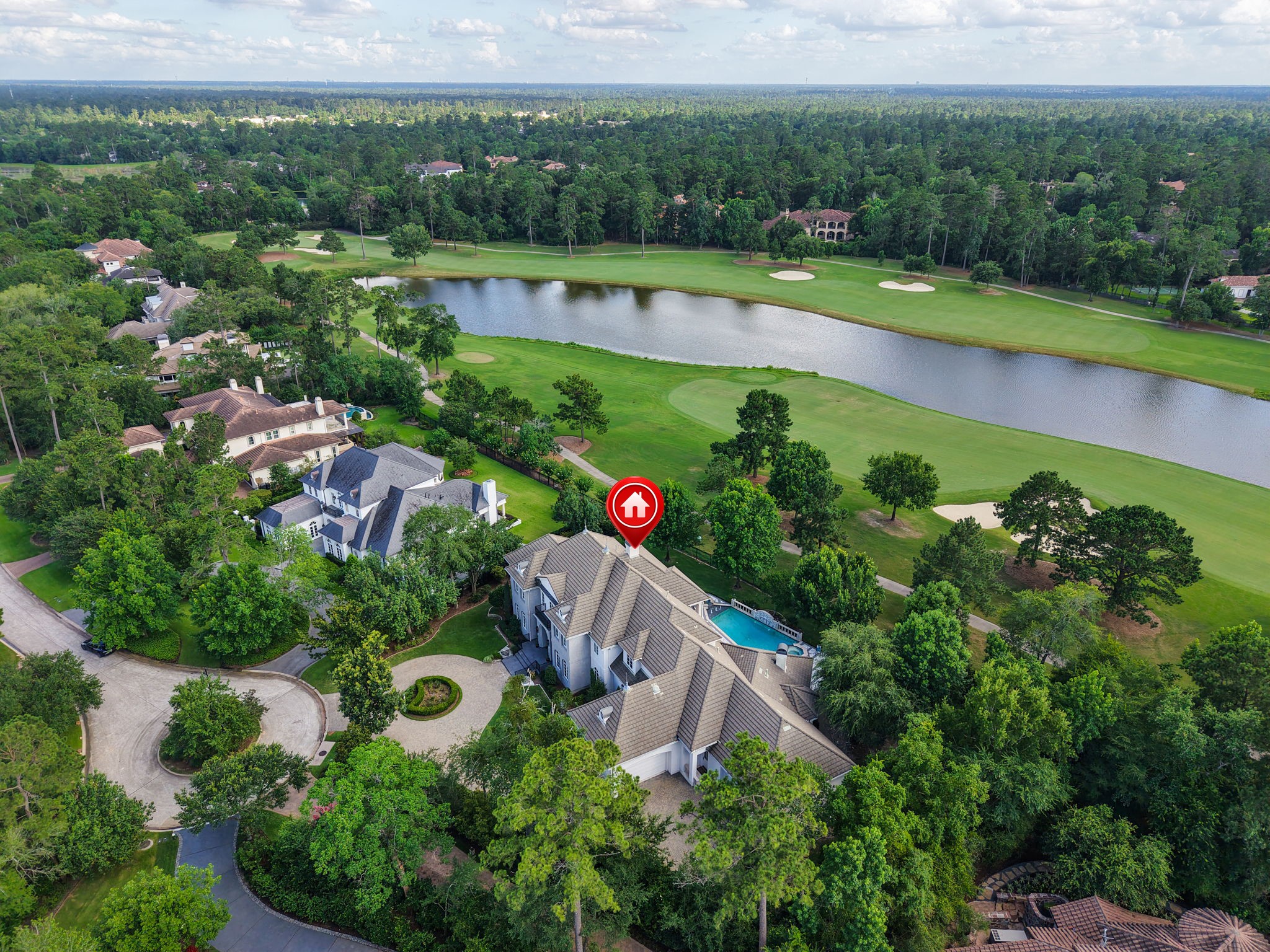 39 Maymont Way Spring, TX 77382 - Photo 47 of 50 This aerial photo showcases a luxurious home in a lush, tree-lined neighborhood adjacent to a golf course. The property features a large, elegant house with a pool, offering scenic views of the course and a nearby water feature. The area is serene and upscale, ideal for those seeking privacy and natural beauty.