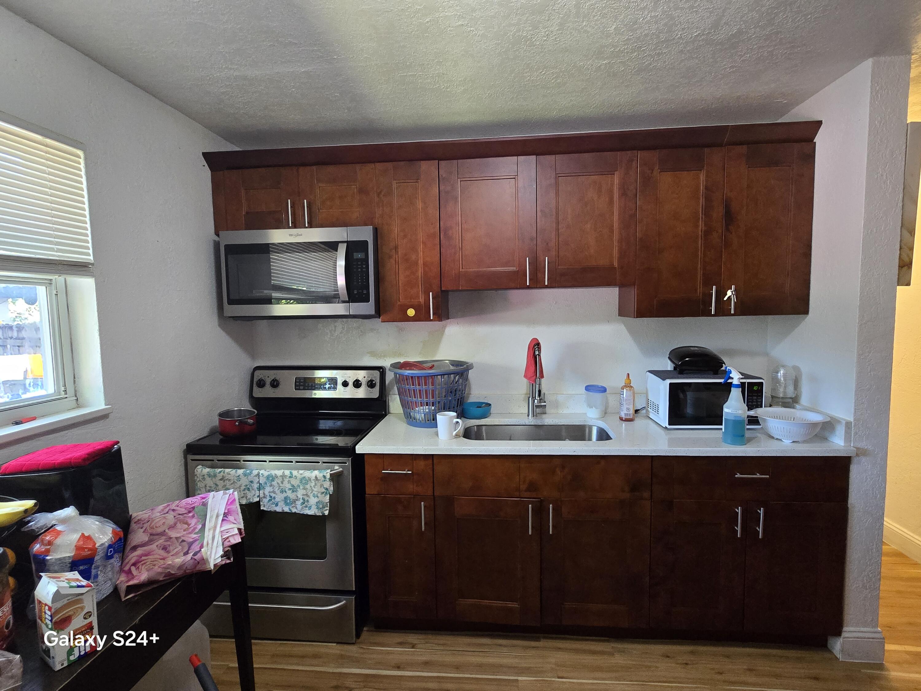 4258 Coconut Road Lake Worth, FL 33461 - Photo 5 of 14 a kitchen with stainless steel appliances granite countertop a sink dishwasher stove top oven and cabinets with wooden floor