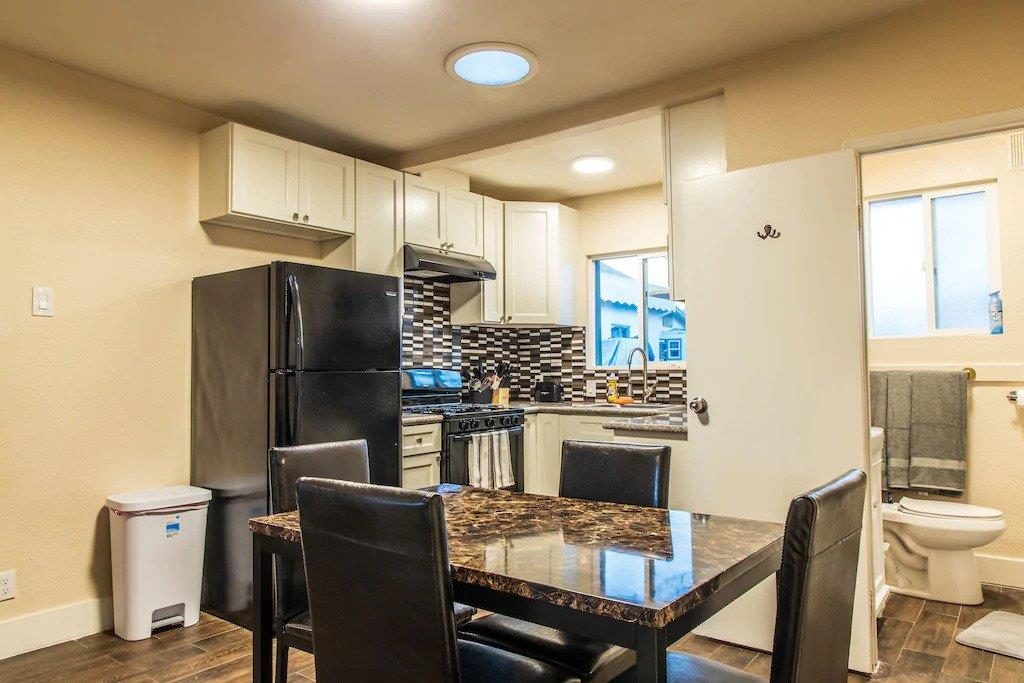 6152 Baker Street Oakland, CA 94608 - Photo 13 of 23 a kitchen with stainless steel appliances granite countertop a dining table chairs refrigerator and sink