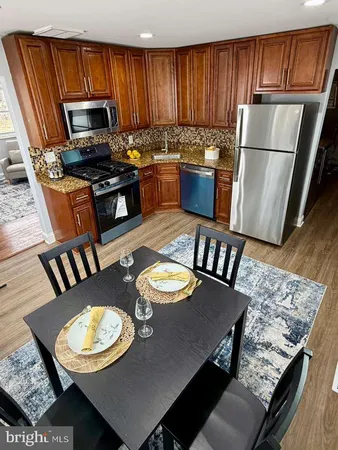 a kitchen with stainless steel appliances granite countertop a stove a refrigerator a dining table and chairs