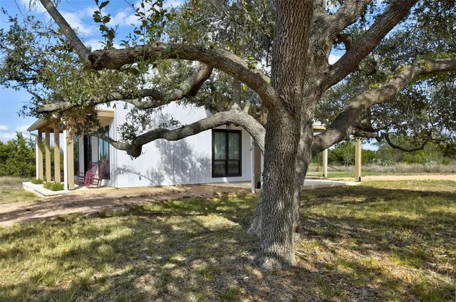 a view of a house with a yard fire pit and a large tree