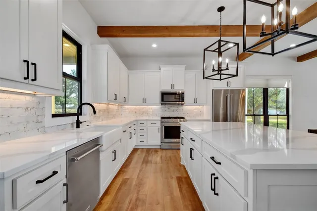 a large white kitchen with kitchen island a sink a stove and cabinets