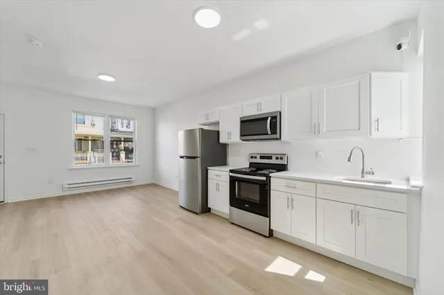 a kitchen with stainless steel appliances a stove top oven a sink a refrigerator a window