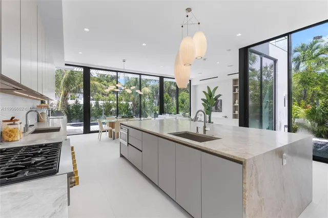 a large kitchen with kitchen island granite countertop a large window and a sink