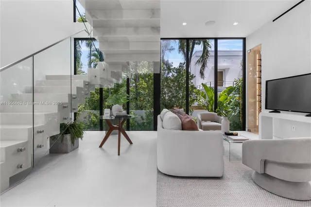 a living room with couches a flat screen tv and a large window with outer view