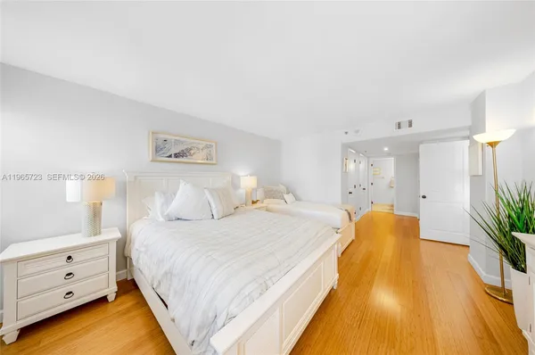 a spacious bedroom with a bed and a potted plant on dresser