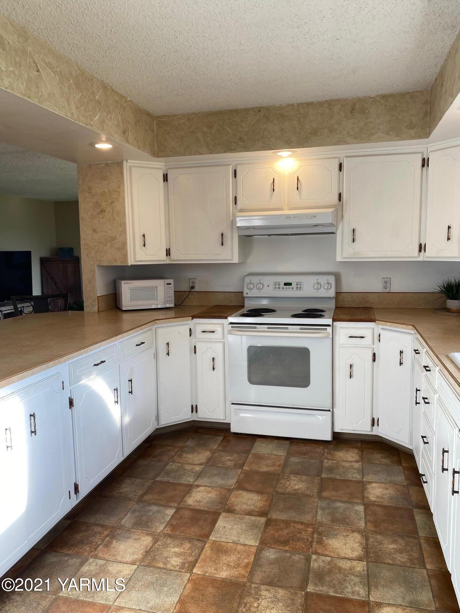 320 Bliss Road Zillah, WA 98953 - Photo 8 of 33 a white kitchen with granite countertop a stove a sink and white cabinets