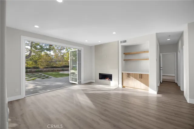 a view of empty room with wooden floor and fireplace