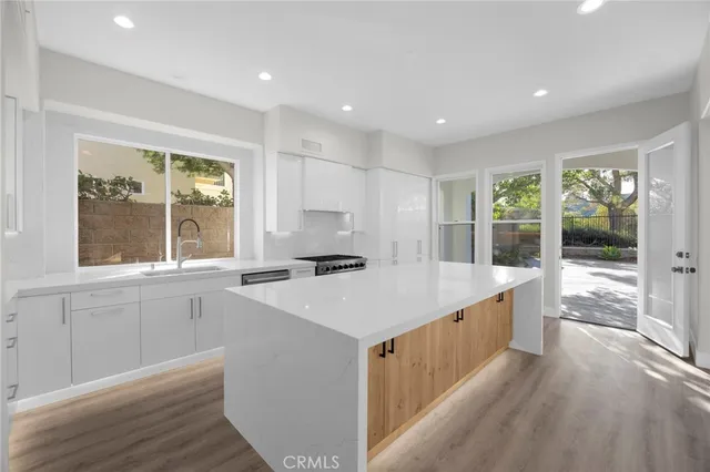 a large kitchen with kitchen island a large window a sink and stainless steel appliances