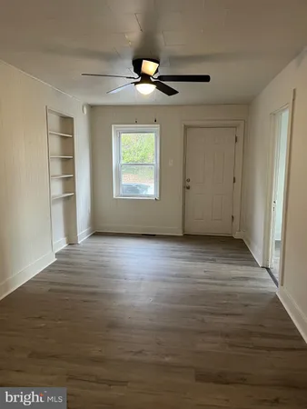 an empty room with wooden floor cabinet and windows