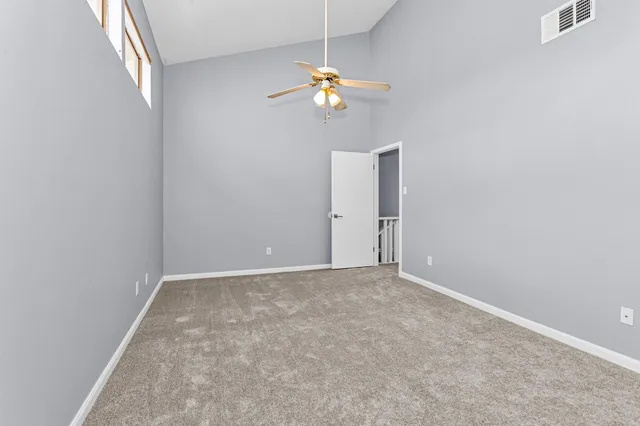 an empty room with a chandelier fan and wooden floor