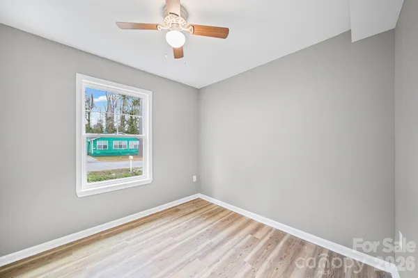 a view of an empty room with window and wooden floor