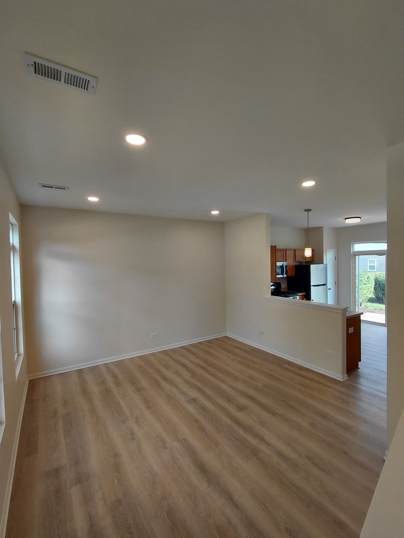 7214 Bradley Drive Plainfield, IL 60586 - Photo 3 of 21 a view of an empty room with wooden floor