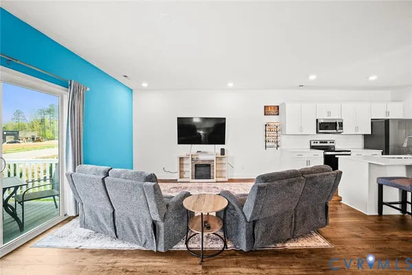a living room with furniture kitchen view and a flat screen tv