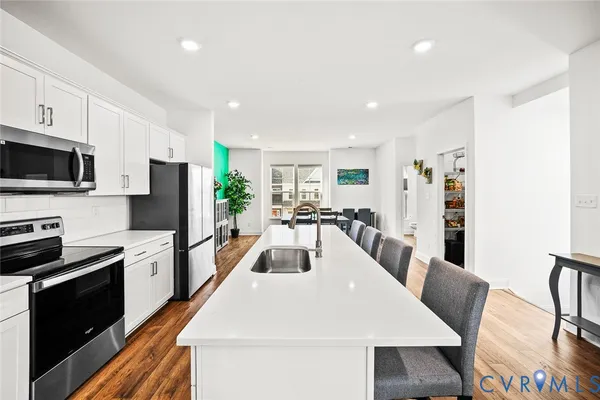 a kitchen with stainless steel appliances a stove a sink a microwave a refrigerator a stove a table and chairs