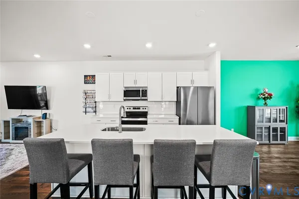 a kitchen with stainless steel appliances a dining table chairs refrigerator and microwave