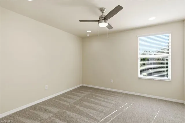 an empty room with a window and a ceiling fan