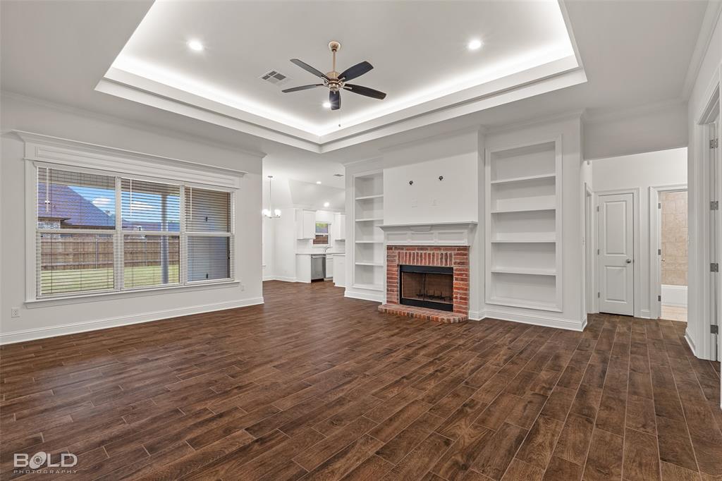 304 Prien Lk Loop Bossier City, LA 71111 - Photo 9 of 39 Living area featuring a brick fireplace, built-in shelving, a tray ceiling with recessed lighting and a ceiling fan, and wood-finish flooring