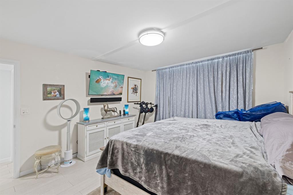 3100 Northeast 49th Street, Unit 206 Fort Lauderdale, FL 33308 - Photo 16 of 39 a bedroom with a bed a mirror and paintings on the wall