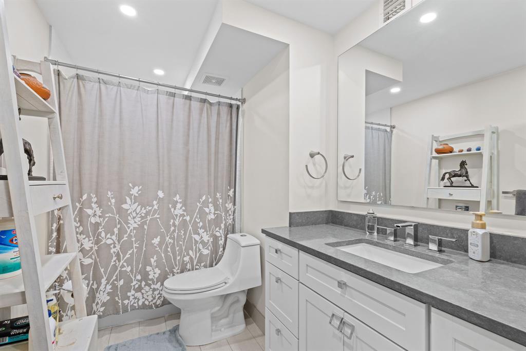 3100 Northeast 49th Street, Unit 206 Fort Lauderdale, FL 33308 - Photo 19 of 39 a bathroom with a granite countertop sink a toilet and a mirror