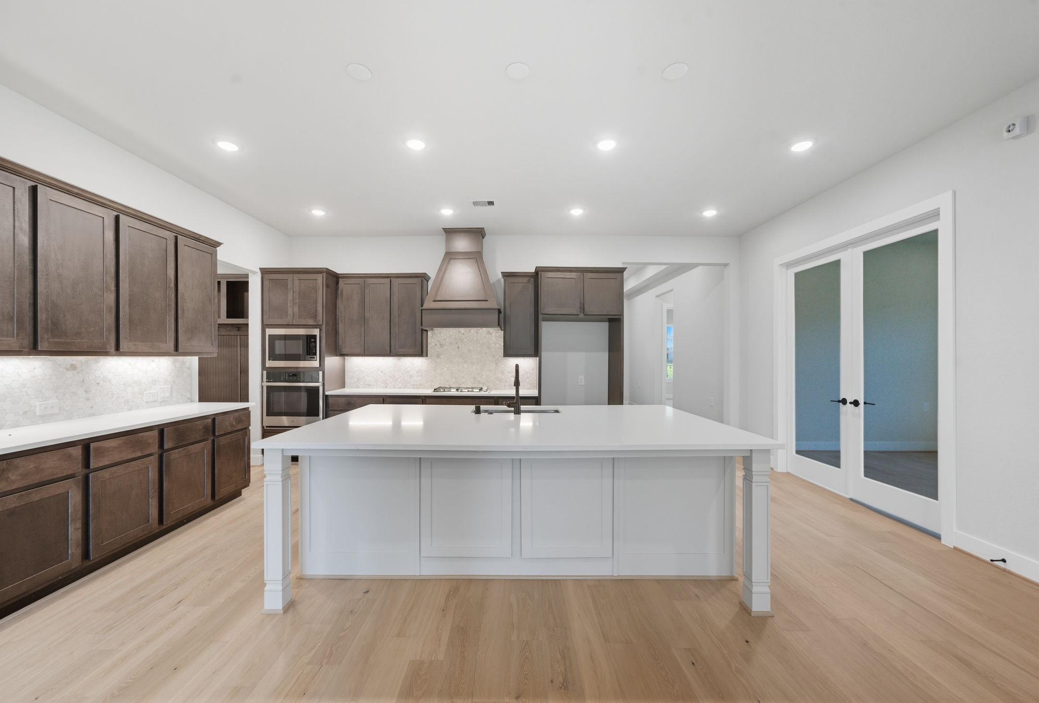 10041 Larkin Cove Willis, TX 77318 - Photo 13 of 48 a large kitchen with stainless steel appliances a large counter top and wooden floors