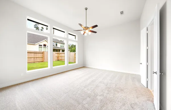 an empty room with windows and ceiling fan