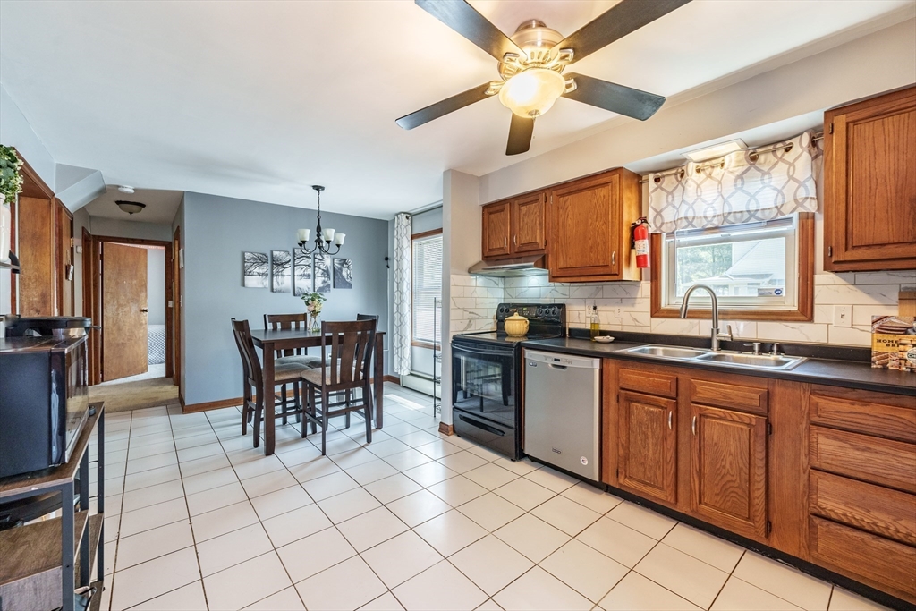 105 Hamilton Street Springfield, MA 01119 - Photo 3 of 35 a kitchen with stainless steel appliances granite countertop a sink a stove a dining table and chairs with wooden floor