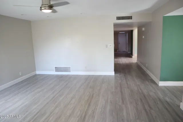 an empty room with wooden floor and windows
