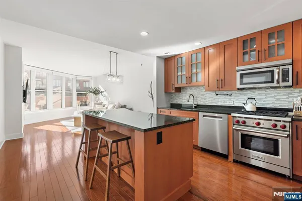 a kitchen with stainless steel appliances granite countertop a stove a sink dishwasher and a microwave oven with wooden floor