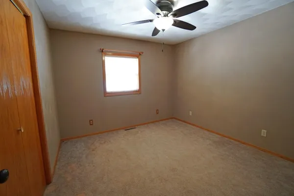 an empty room with a window and a fan