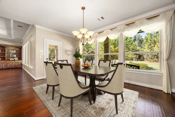 a view of a dining room and livingroom with furniture wooden floor a chandelier