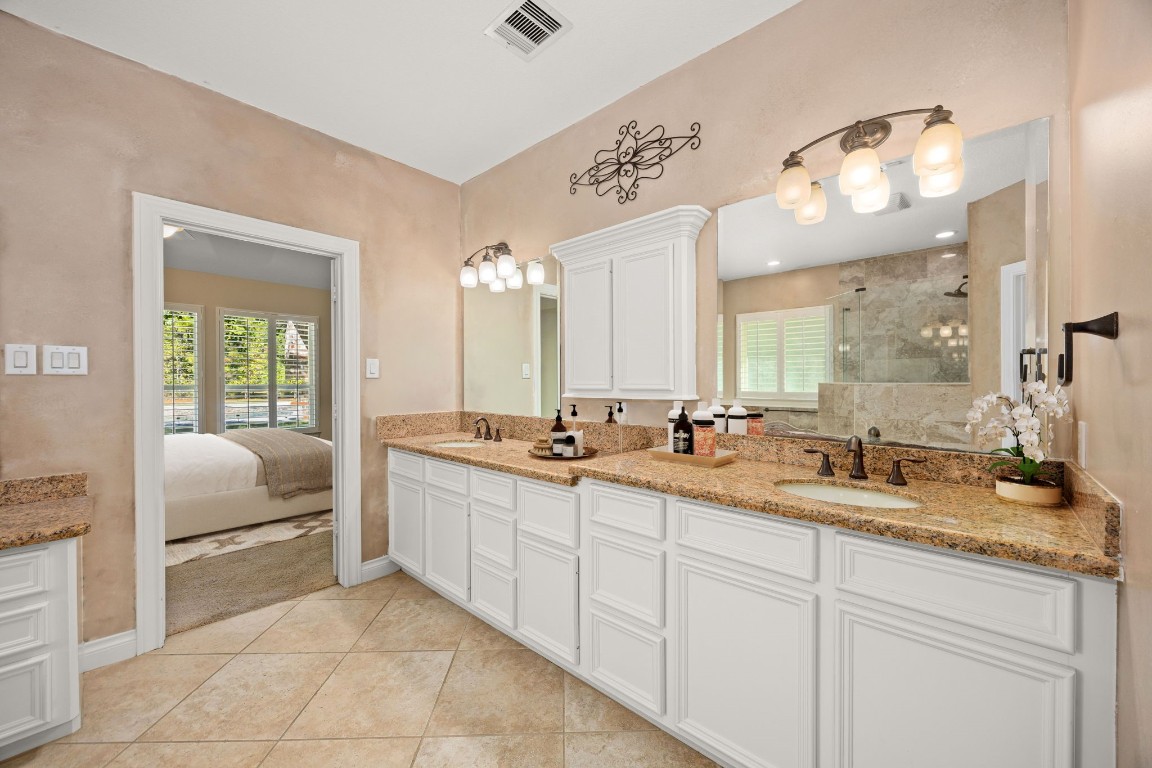 13506 Stagecoach Road Magnolia, TX 77355 - Photo 15 of 37 The primary bath offers a spa-like retreat with dual vanities, granite countertops, and elegant lighting. A spacious walk-in shower and neutral tile finishes create a serene, relaxing atmosphere, perfect for unwinding after a long day.