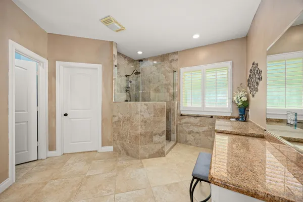 a spacious bathroom with a granite countertop bathtub sink and mirror