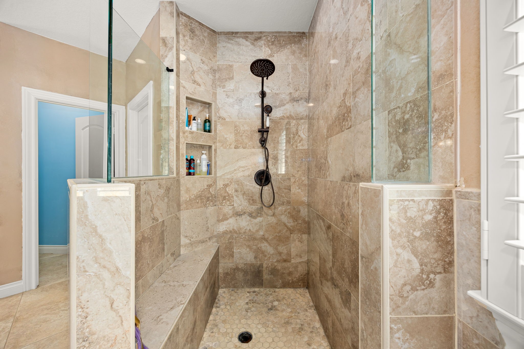 13506 Stagecoach Road Magnolia, TX 77355 - Photo 17 of 37 The walk-in shower offers a true spa-like experience with elegant tile from floor to ceiling, a built-in bench, recessed shelving, and a rainfall showerhead, creating the perfect space to unwind in comfort and style.