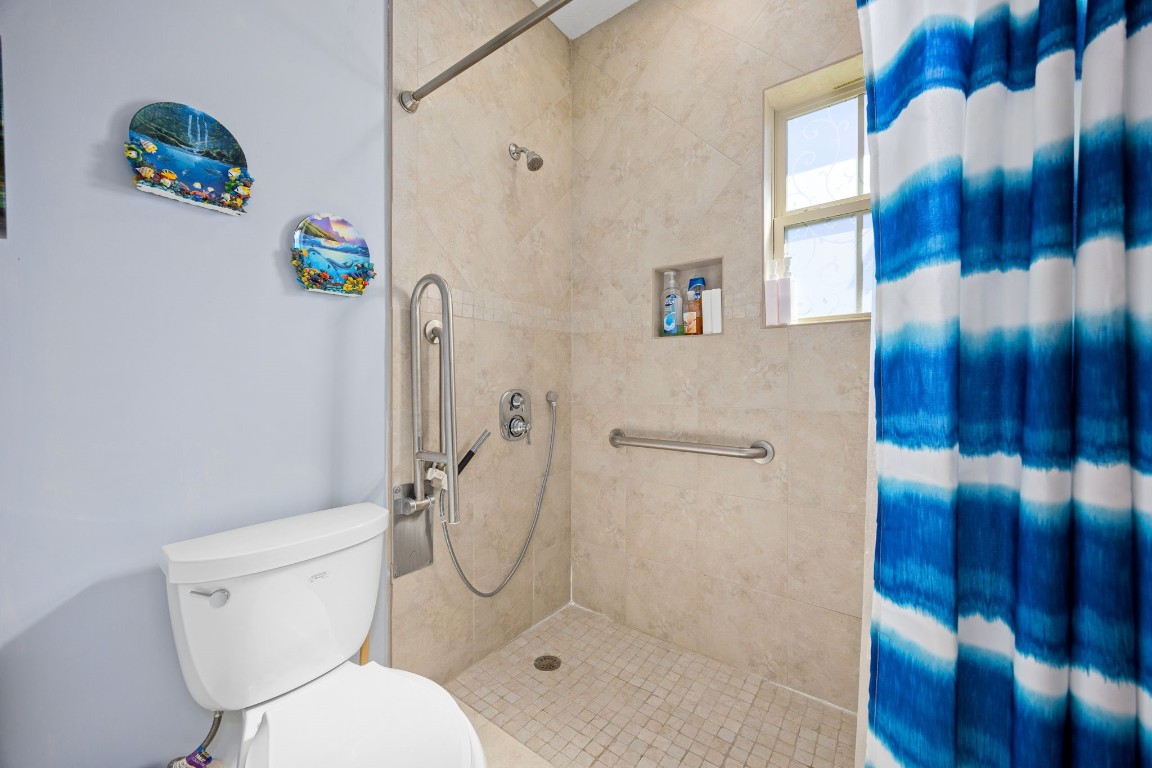 13506 Stagecoach Road Magnolia, TX 77355 - Photo 23 of 37 This secondary bath features a beautifully tiled walk-in shower with accessibility upgrades, including grab bars and a handheld showerhead, combining style with thoughtful functionality.