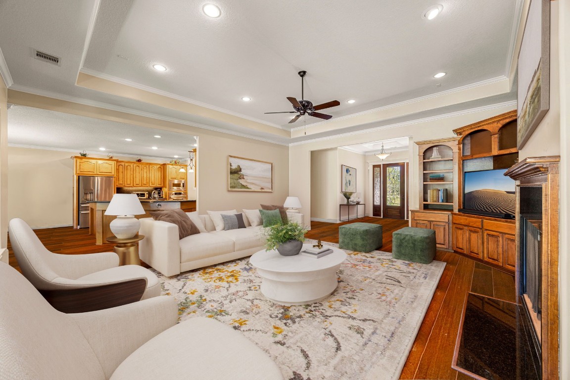 13506 Stagecoach Road Magnolia, TX 77355 - Photo 7 of 37 This inviting living room exudes warmth and elegance with its tray ceiling details, hardwood flooring, and beautiful built-in cabinetry framing the fireplace. Expansive windows offer serene views and fill the space with soft natural light, creating the perfect setting for relaxing evenings or lively gatherings.