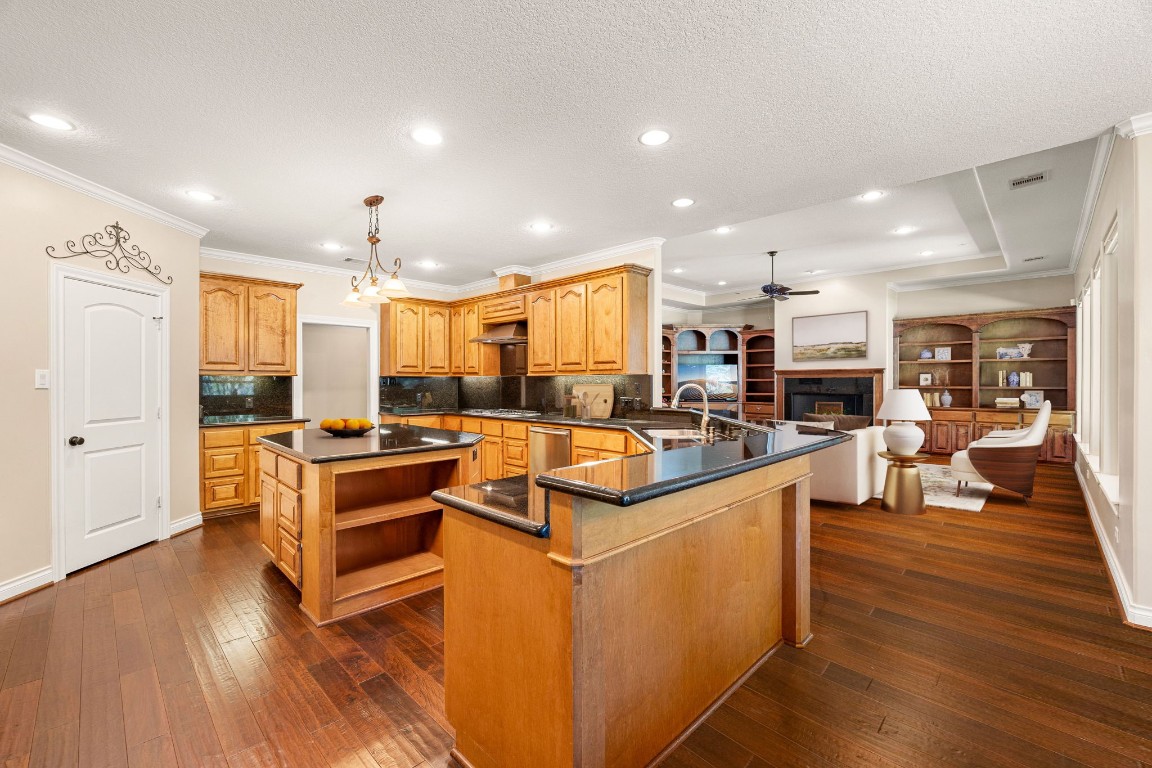 13506 Stagecoach Road Magnolia, TX 77355 - Photo 9 of 37 This expansive kitchen blends warmth and functionality with rich wood cabinetry, sleek granite countertops, and a spacious center island perfect for meal prep or gathering. Overlooking the inviting living area, the open layout enhances flow and connection, while recessed lighting and elegant crown molding add a touch of sophistication.