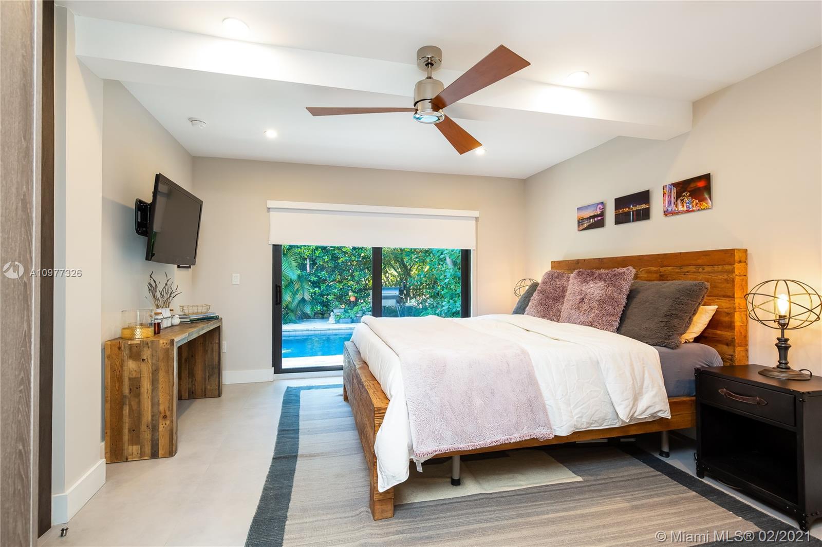 5185 Alton Road Miami Beach, FL 33140 - Photo 13 of 41 a spacious bedroom with a bed and a flat screen tv