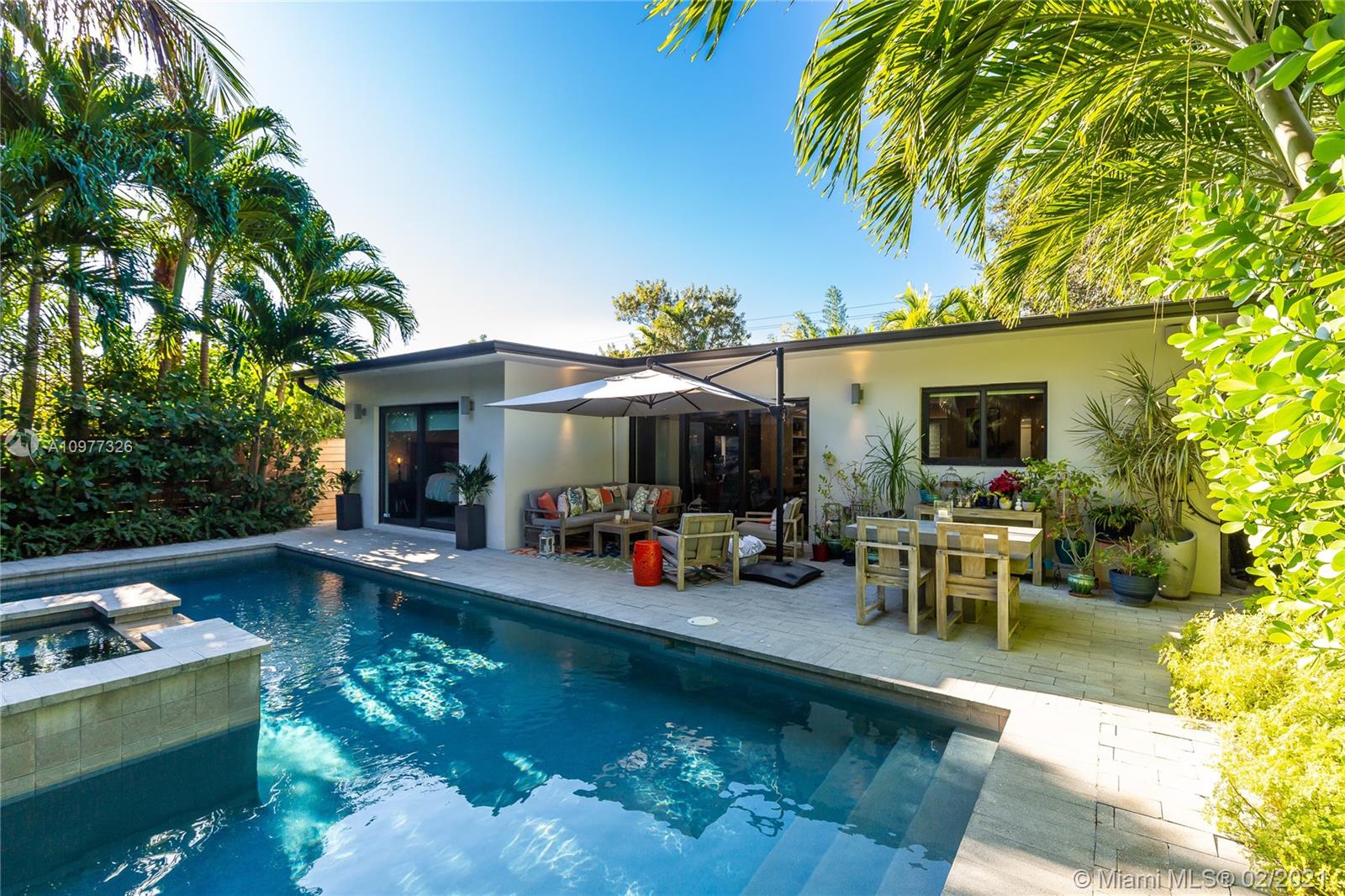 5185 Alton Road Miami Beach, FL 33140 - Photo 29 of 41 a view of a patio with table and chairs potted plants and a palm tree