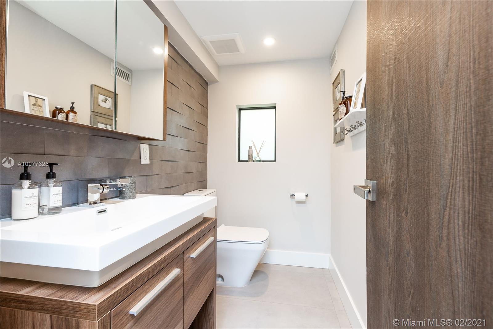 5185 Alton Road Miami Beach, FL 33140 - Photo 32 of 41 a bathroom with a sink a toilet and a mirror