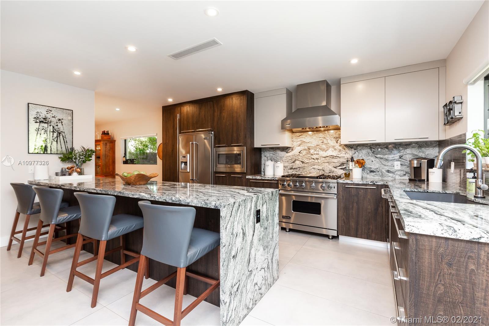 5185 Alton Road Miami Beach, FL 33140 - Photo 6 of 41 a kitchen with stainless steel appliances kitchen island granite countertop a stove top oven a sink a dining table and chairs