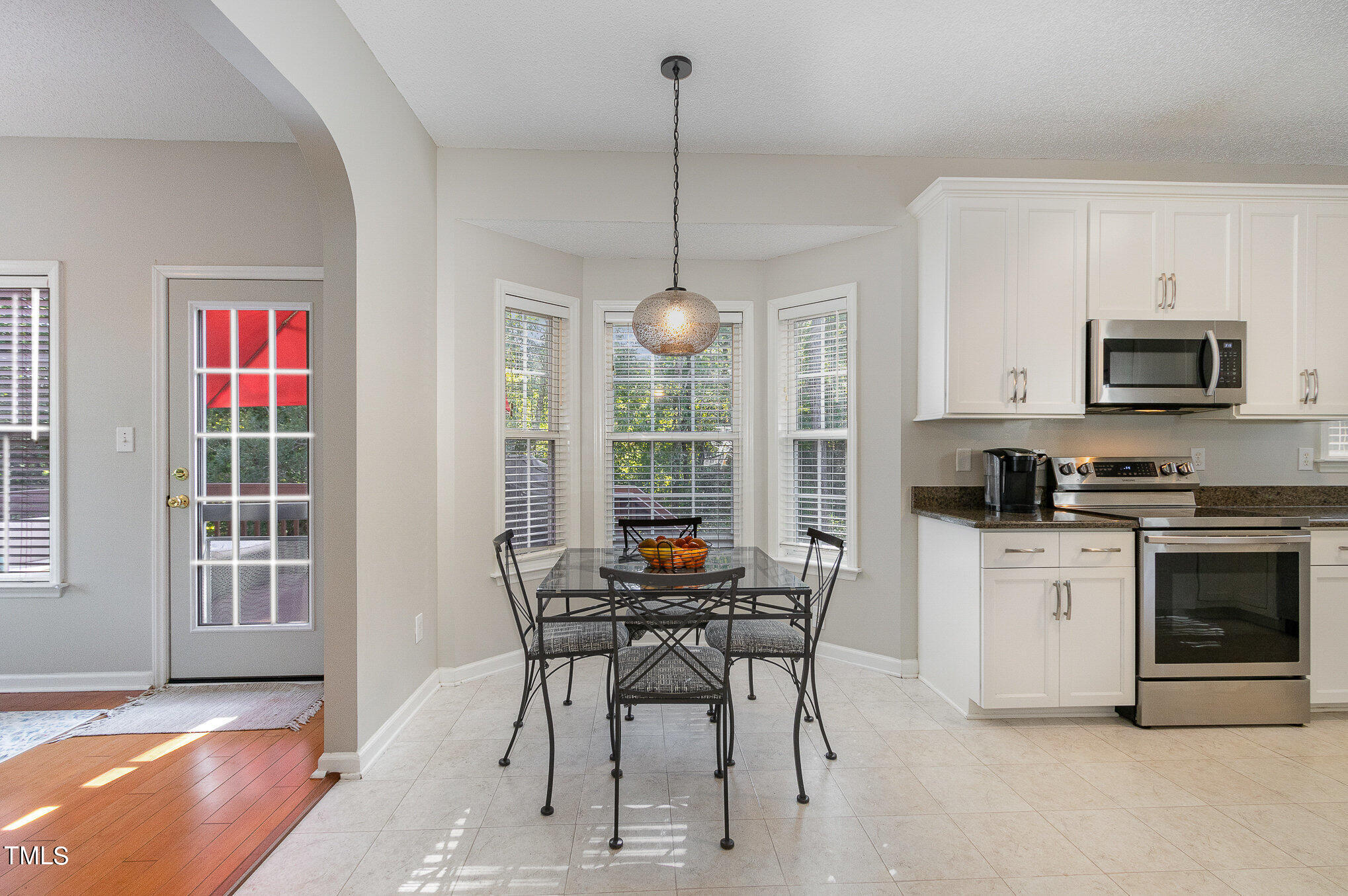 9221 Shallcross Way Raleigh, NC 27617 - Photo 8 of 28 a kitchen with stainless steel appliances granite countertop a stove top oven a sink dishwasher a dining table and chairs with wooden floor