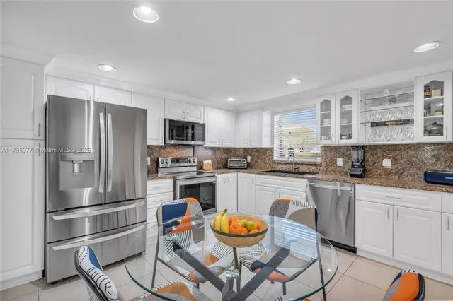 a kitchen with granite countertop stainless steel appliances a refrigerator and a stove top oven