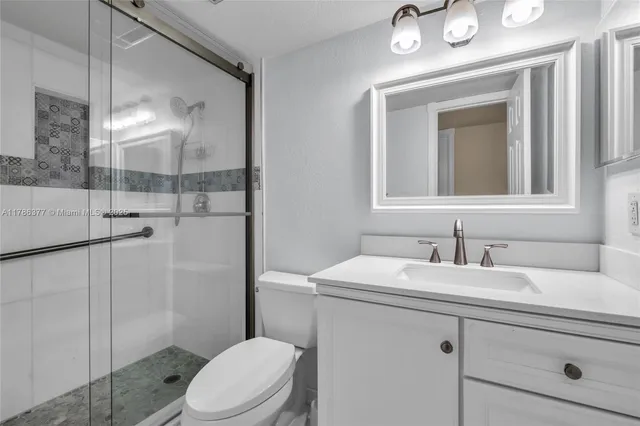 a bathroom with a toilet sink vanity and mirror