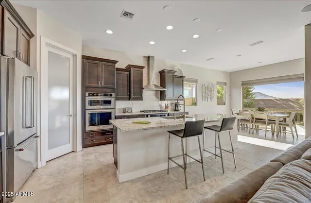 a kitchen with stainless steel appliances kitchen island granite countertop a refrigerator and cabinets