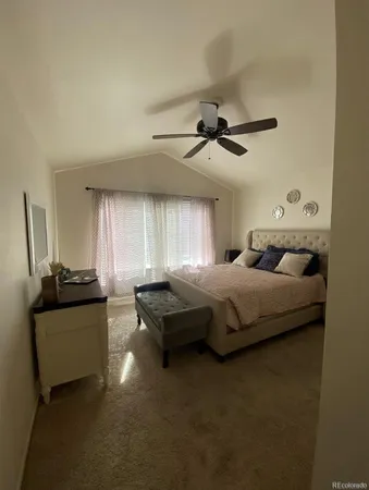 a bedroom with a large bed and a chandelier fan