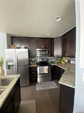 a kitchen with stainless steel appliances kitchen island granite countertop a refrigerator a sink and a stove