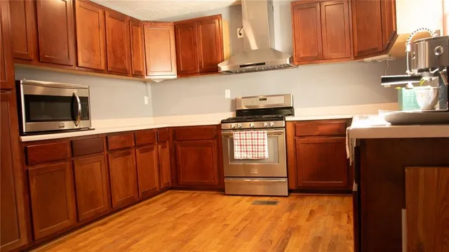 a kitchen with stainless steel appliances granite countertop a stove a sink dishwasher and a microwave oven with cabinets