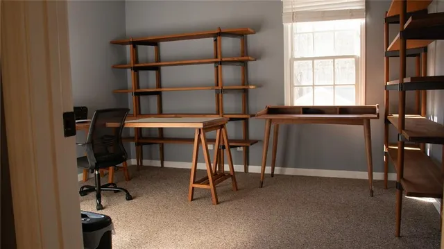 a view of a workspace with furniture and a window