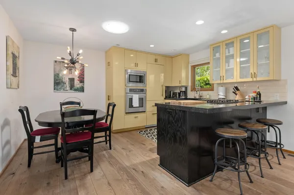 a kitchen with stainless steel appliances granite countertop a table chairs and a refrigerator